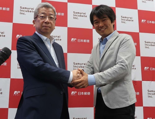 笑顔で握手する横山・日本郵便社長と榊原・サムライインキュベート社長