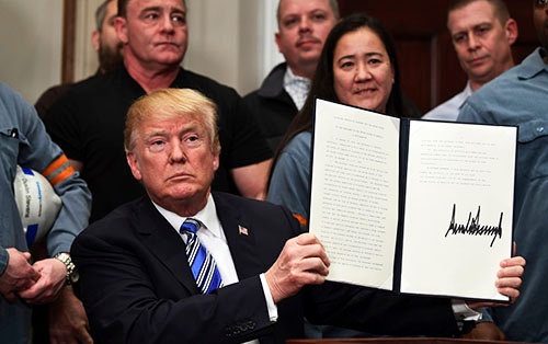 3月8日、トランプ米大統領はホワイトハウスで労働者らに囲まれ、鉄鋼とアルミニウムの輸入制限措置を命じる大統領告示に署名した（写真：AP/アフロ）