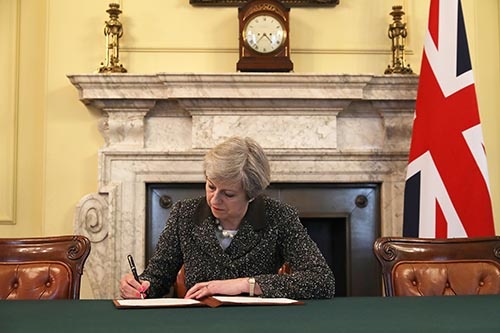 3月29日、英国のメイ首相はEU基本条約(リスボン条約)50条を発動し、EUに対して離脱を正式に通知した。EU離脱を正式通告する書簡に署名するメイ首相 (写真:PA Photos/amanaimages)