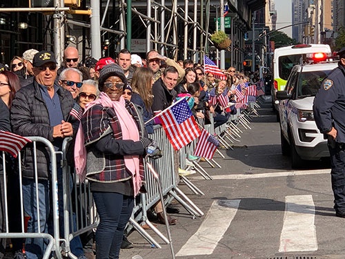 沿道で国旗を手にベテランズデーのパレードを待つ米国市民たち。トランプ派と反対派の間で口論になる場面も見られた