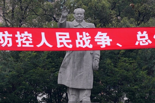 毛沢東の像。新型コロナウイルス感染との戦いを人民戦争とする横断幕が張られている（写真：ロイター/アフロ）
