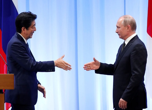 笑顔で握手を求めるのは安倍首相だけ?(写真:代表撮影/ロイター/アフロ)