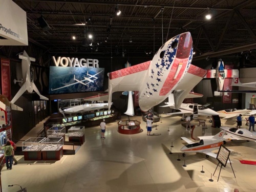 EAA航空博物館のバート・ルータン関連展示。上からつり下げられているのが、「スペースシップ・ワン」。奥のパネルが「ヴォイジャー」。