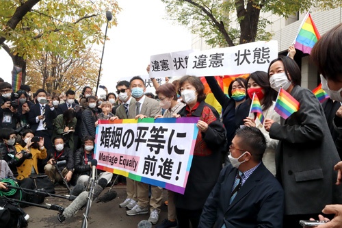 11月30日、東京地裁の前で旗を掲げる原告と弁護団。現場では「違憲」の文字に拍手が湧き起こった