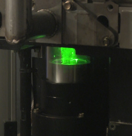サファイアガラスのシリンダーの中に緑のレーザー光を当てている。グリーンの円柱のように見えているのが、空気と燃料が混じった混合気の渦だ。