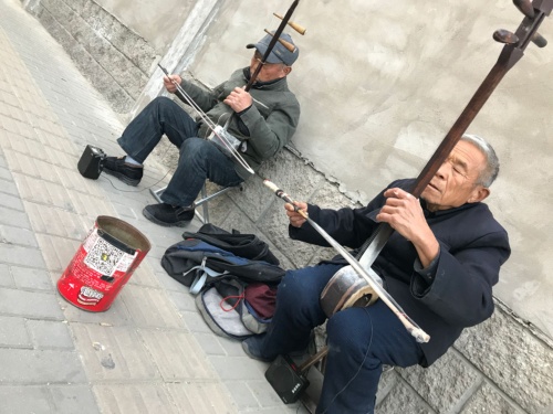 北京の街角で演奏する老人たち。おひねり入れにはQRコードが貼ってある。筆者はウィーチャットペイを使って5元を支払った。(2018年11月、筆者撮影)