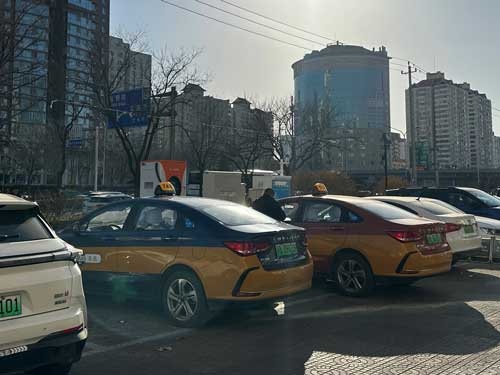 北京のEVタクシーと充電を待つ運転手（撮影は筆者）