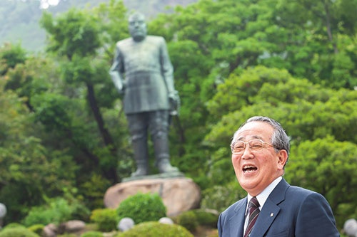 鹿児島県にある西郷隆盛像の前で笑顔を見せる稲盛氏。撮影直前まで土砂降りだったが、足元が悪い中でも嫌な顔ひとつせず歩いて撮影に応じたという