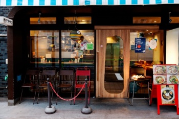 「この店はカフェ？」と間違える人も多そうな、青と白が印象的なオシャレな本店「ソラノイロ Japanese soup noodle free style」の外観。ガラス張りで開放感がある